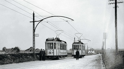 Im Jahr 1909 stehen bei Bochum zwei kleine Straßenbahnen an einem Feld