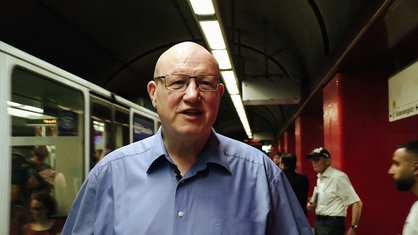 Nahaufnahme Ludwig Schönefeld. Er steht in einer U-Bahn Station.