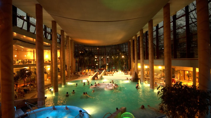 Große, schwach beleuchtete Halle in einer Therme mit einem großen Schwimmbecken