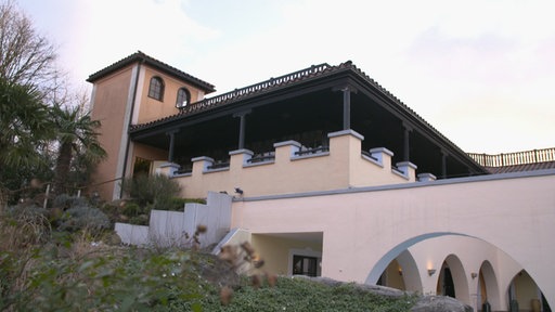 Foto eines Gebäudes mit einer hellen Fassade und brauner Holzüberdachung
