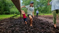 Kinder gehen durch den Matschboden im Großen Torfmoor