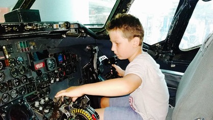 Ein kleiner Junge sitzt im Cockpit eines Flugzeugs.