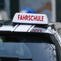 Ein Auto von hinten mit dem Schild "Fahrschule" auf dem Dach.