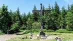 Das Gipfelkreuz auf dem Langenberg. Rundherum stehen Bäume.