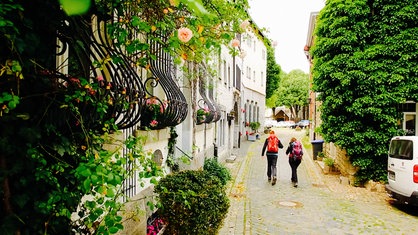 Ein Mann und eine Frau wandern eine von Blumen gesäumte Straße entlang.