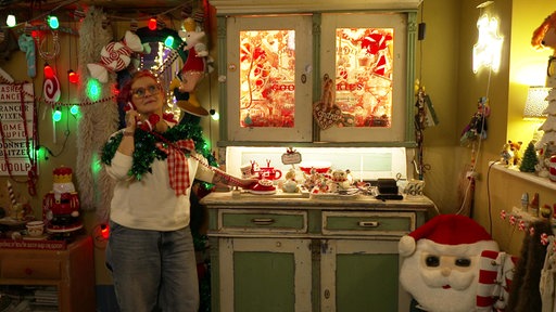 Andrea Stolzenberger steht im komplett weihnachtlich geschmückten Wohnzimmer ihres Hauses in Solingen und hat einen Telefonhörer am Ohr.