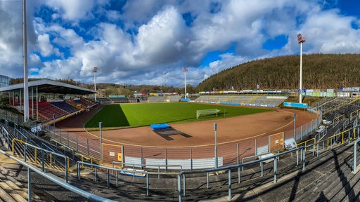 Die leeren Tribünen und der Platz des Leimbachstadions in Siegen unter blauem Himmel