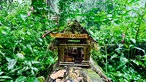 Ein kleines Häuschen im Wald, bestend aus Ästen und Stöcken, dient als Friseursalon.