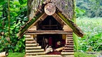 In einem kleinen Häuschen aus Holz, liegen gebastelte Fitnessgeräte, wie zum Beispiel Hanteln aus keineren Baumstöcken.