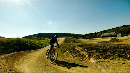 Eine Mountainbikerin fährt um eine enge Kurve im Bikepark des Erlebnisbergs Kappe