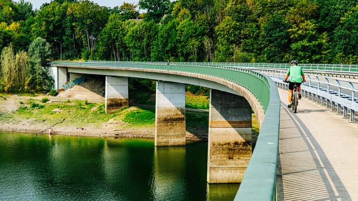 Eine Person überfährt mit dem Fahrrad eine Brücke auf der Radroute  Wasserquintett im Bergischen Land
