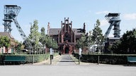 Frontalansicht Zeche Zollern. Ein rotes Backsteingebäude mit spitzem Dach und vielen Verzierungen.