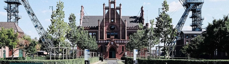 Frontalansicht Zeche Zollern. Ein rotes Backsteingebäude mit spitzem Dach und vielen Verzierungen.