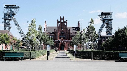 Frontalansicht Zeche Zollern. Ein rotes Backsteingebäude mit spitzem Dach und vielen Verzierungen.