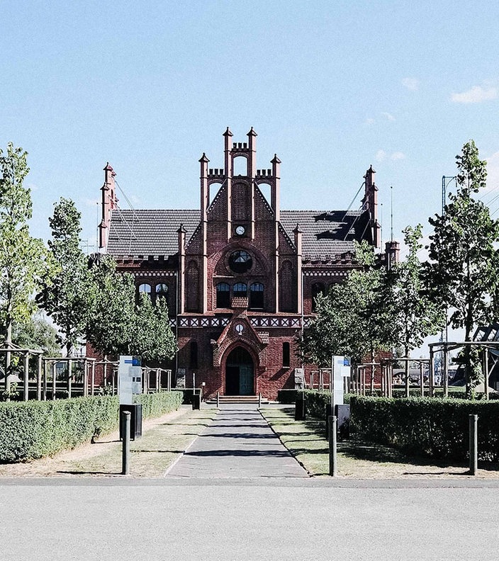 Frontalansicht Zeche Zollern. Ein rotes Backsteingebäude mit spitzem Dach und vielen Verzierungen.