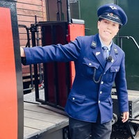 Leo steht stolz, gekleidet in seine Uniform, an einem historischen Eisenbahnwagon.
