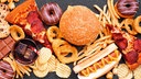 Das Beitragsbild des Dok 5 "Fastfood - Gute Geschäfte mit schnellem Essen" zeigt einen Mix aus Fastfood verteilt auf dunklem Hintergrund. Pizza, Hamburger, Frittten, Chips, Hot Dog, Süßigkeiten 