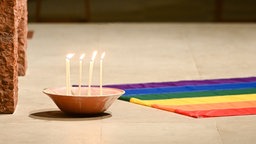 Das Beitragsbild des WDR3 Kulturfeature "Herz über Kreuz" zeigt den Altar der Paulskirche, Kerzen und eine Regenbogenfahne.