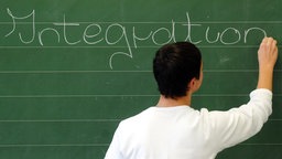 Ein Schüler schreibt das Wort "Integration" an eine Tafel