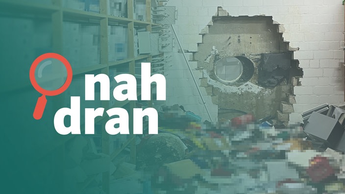 Das Bild zeigt den Tatort. Die Täter haben ein großes Loch in die Wand gebohrt. Viele Gegenstände liegen auf dem Boden. Im Vordergrund steht das Logo von "nah dran". 