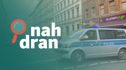 Ein Absperrband und rechts davon ein Polizeiauto auf einer Straße in Berlin. Links das Logo von nah dran.