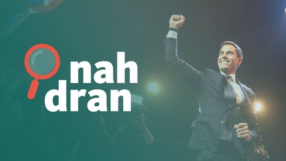 Der Wahlsieger Rob Jetten steht auf einer Bühne und hebt die rechte Faust. Links das Logo von nah dran.
