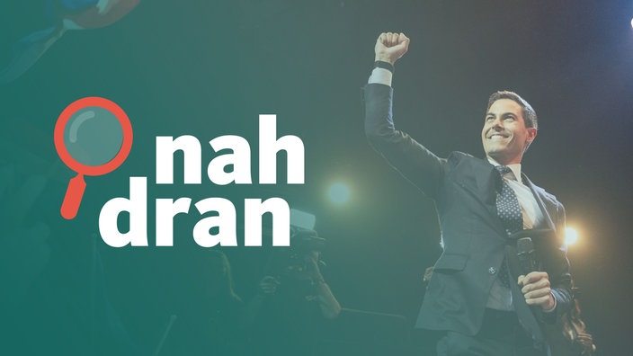 Der Wahlsieger Rob Jetten steht auf einer Bühne und hebt die rechte Faust. Links das Logo von nah dran.