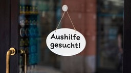 Schild in einem Schaufenster mit der Aufschrift: "Aushilfe gesucht!"