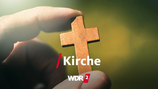 Eine Hand hält ein Holzkreuz