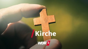 Eine Hand hält ein Holzkreuz