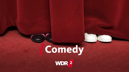 Zwei Paar Schuhe lugen unter einem roten Vorhang hervor. 