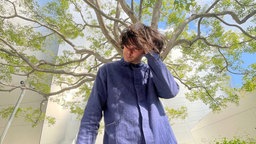 David Longstreh, Sänger der Band Dirty Projectors, posiert vor einem Baum.