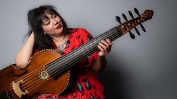 Die Gambistin Águeda Macias lächelnd mit ihrem Instrument in den Händen.