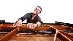Der Pianist udn Dirigent Frank Dupree sitzt vor einem geöffneten Flügel.