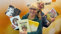 Ulla Scholz und Heike Knispel stehen im WDR 4-Studio und halten fünf Kochbuchempfehlungen in den Händen