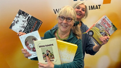 Ulla Scholz und Heike Knispel stehen im WDR 4-Studio und halten fünf Kochbuchempfehlungen in den Händen