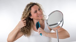 Eine Frau kämmt sich die Haare mit einer Bürste.