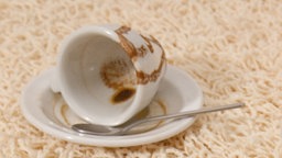 Ein heller Teppich, auf dem eine umgekippte Espressotasse liegt