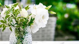 In einer Kristallvase steht ein Strauß von weißen Blumen