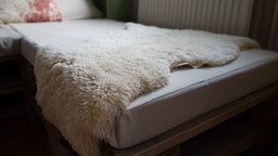 Ein Lammfell liegt auf einem Sofa.