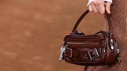 Frauenhand trägt braune Ledetasche