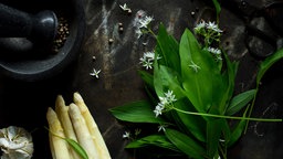 Spargel und Bärlauch liegen auf einem schwarzen Untergrund. 