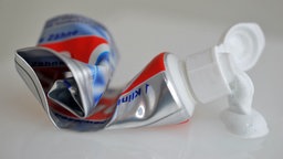 Aus einer zerquetschten Tube tropft Zahnpasta