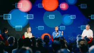 Podiumsdiskussion beim WDR Europaforum 2026 in Berlin: Auf der Bühne (von rechts) Jan van Aken, Jana Puglierin und Margarita Šešelgytė 