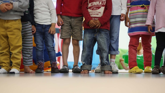 Symbolbild: Beine und Füße unterschiedlicr Kinder, barfuß und mit Schuhen
