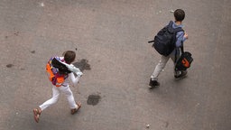 Kinder auf einem Schulhof mit Schulranzen