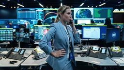 Szene aus dem Film "A House of Dynamite": Rebecca Ferguson als Captain Olivia Walker steht telefonierend in einem Kontrollraum, umgeben von Bildschirmen.