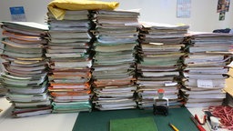Symbolbild Bürokratieabbau: Stapel mit Akten liegen auf einem Schreibtisch