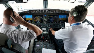 Pilot (l) und Erster Offizier führen vor dem Start einen Vorflugcheck im Cockpit einer Boeing 737 Max durch. 