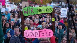 "Wir sind das Stadtbild" steht auf einem Plakat, das ein Demonstrant vor dem Brandenburger Tor hält. 